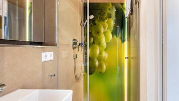 Un bagno moderno con box doccia in vetro, lavandino bianco e specchio.