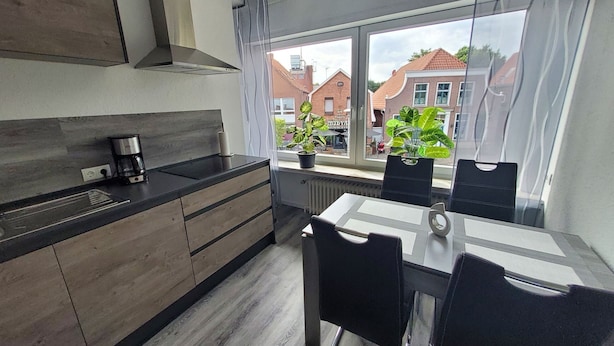 Una cocina moderna con comedor, ventanas amplias y plantas en macetas.