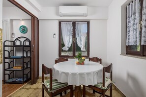 Un comedor con una mesa redonda, sillas, una planta pequeña y una estantería.