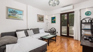 A modern room with a bed, a desk, and a chair. There are paintings on the walls and a window with a view of trees. - House Rose With Private Pool And Garden (Krk)