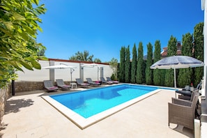 Una piscina con sillas de descanso y una mesa con sombrilla.