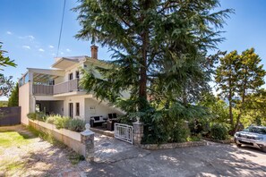 A two-story house with a balcony, a stone entrance, and a parked car. - House Rose With Private Pool And Garden (Krk)
