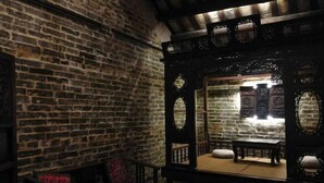 Une pièce à l’ambiance traditionnelle, avec un mur en briques, un banc en bois et une table.