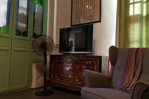A room with a television on a wooden cabinet, a fan, and a sofa. - Jinshidi Inn (Guangzhou)