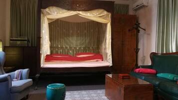 A room with a bed, a green sofa, a wooden cabinet, and a small table.