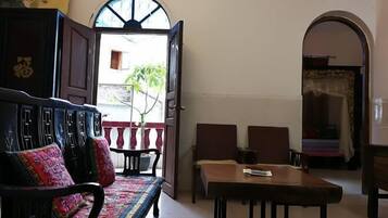 A room with a sofa, a table, and an open door leading outside.