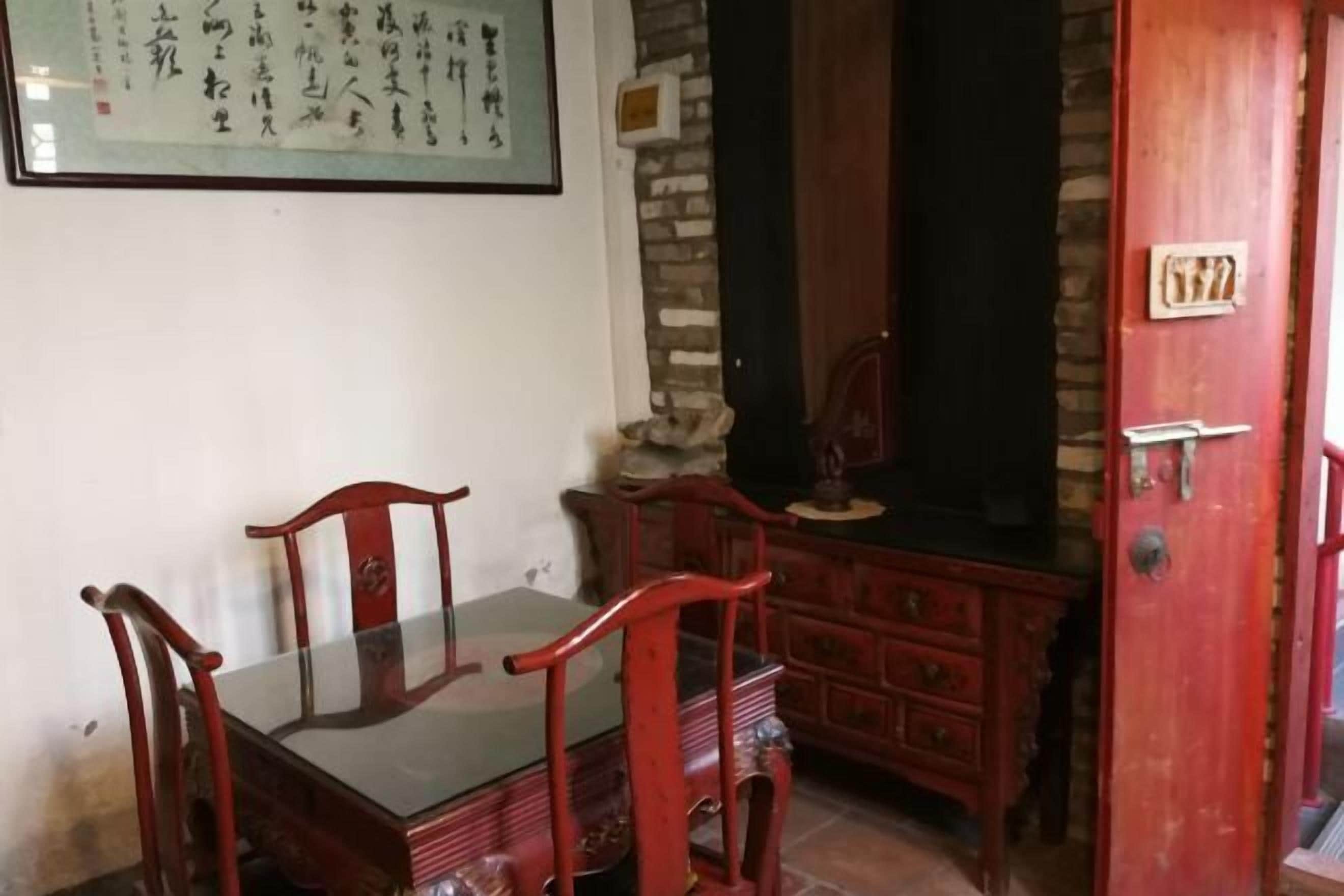 Un comedor tradicional con una mesa y sillas de madera, un muro de piedra y una puerta roja con una placa numérica.