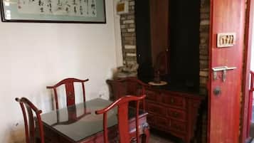 Un comedor tradicional con una mesa y sillas de madera, un muro de piedra y una puerta roja con una placa numérica.