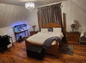 Une chambre à coucher avec un lit en bois, un aquarium, un bureau et un lustre.