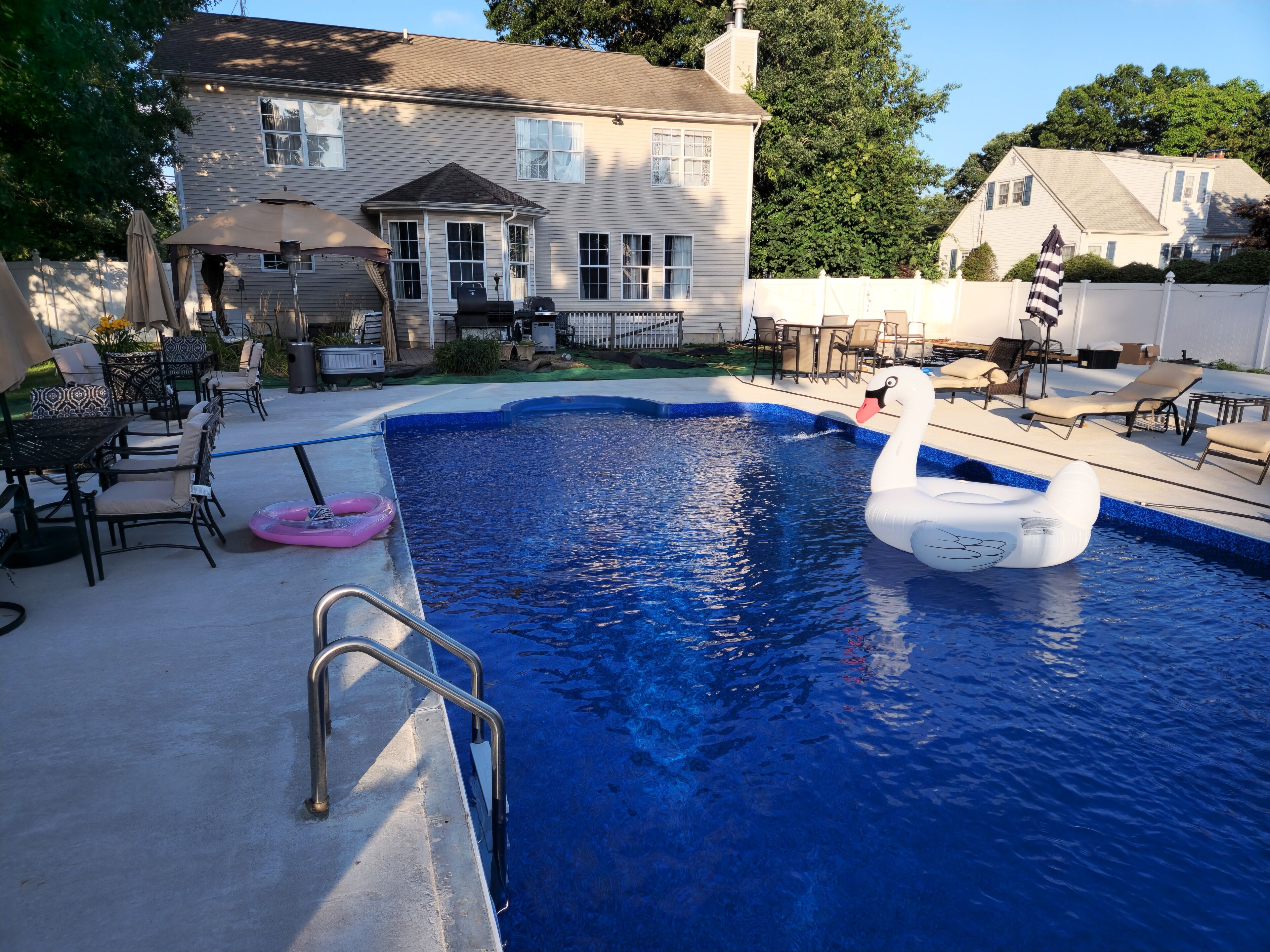 A backyard with a swimming pool, outdoor furniture, and a swan float.