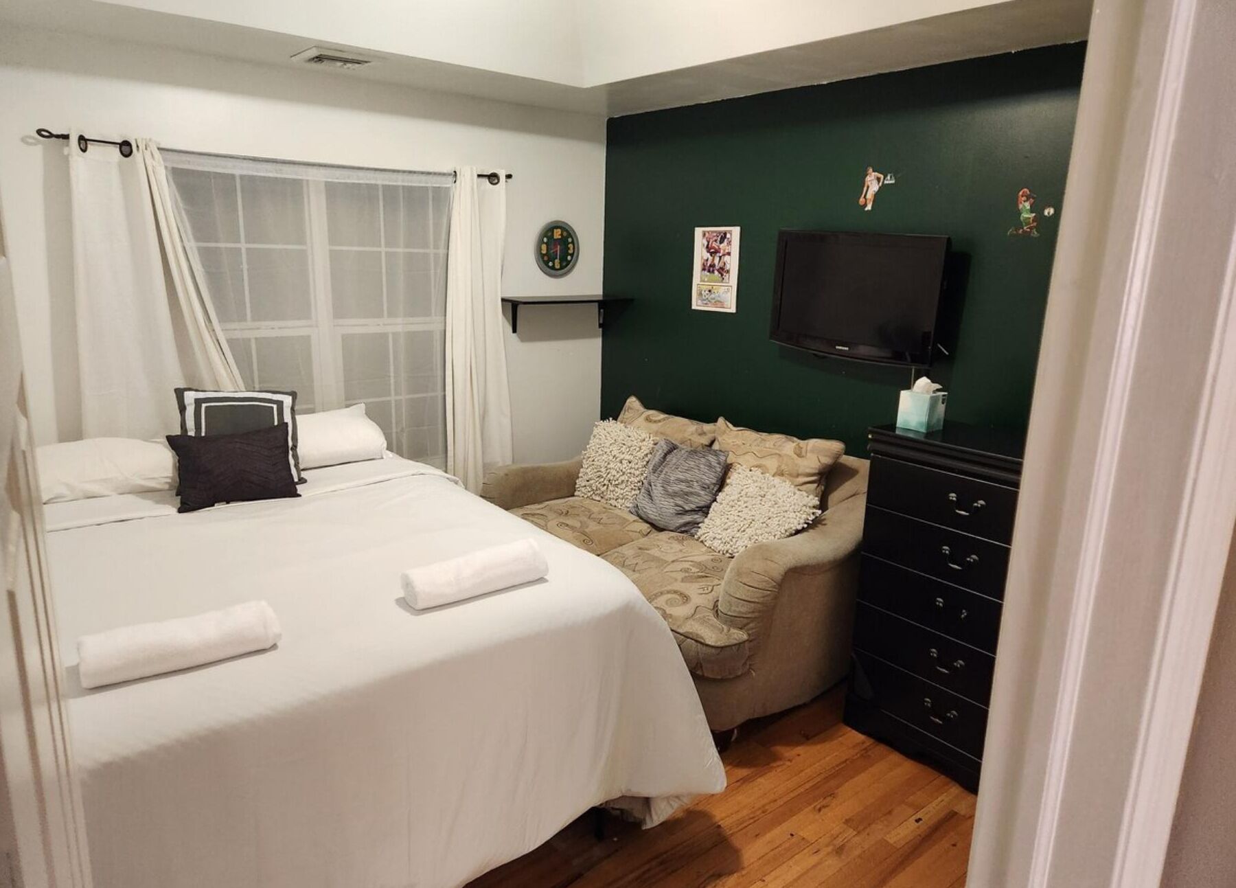 A bedroom with a bed, a sofa, a TV, and a dresser.