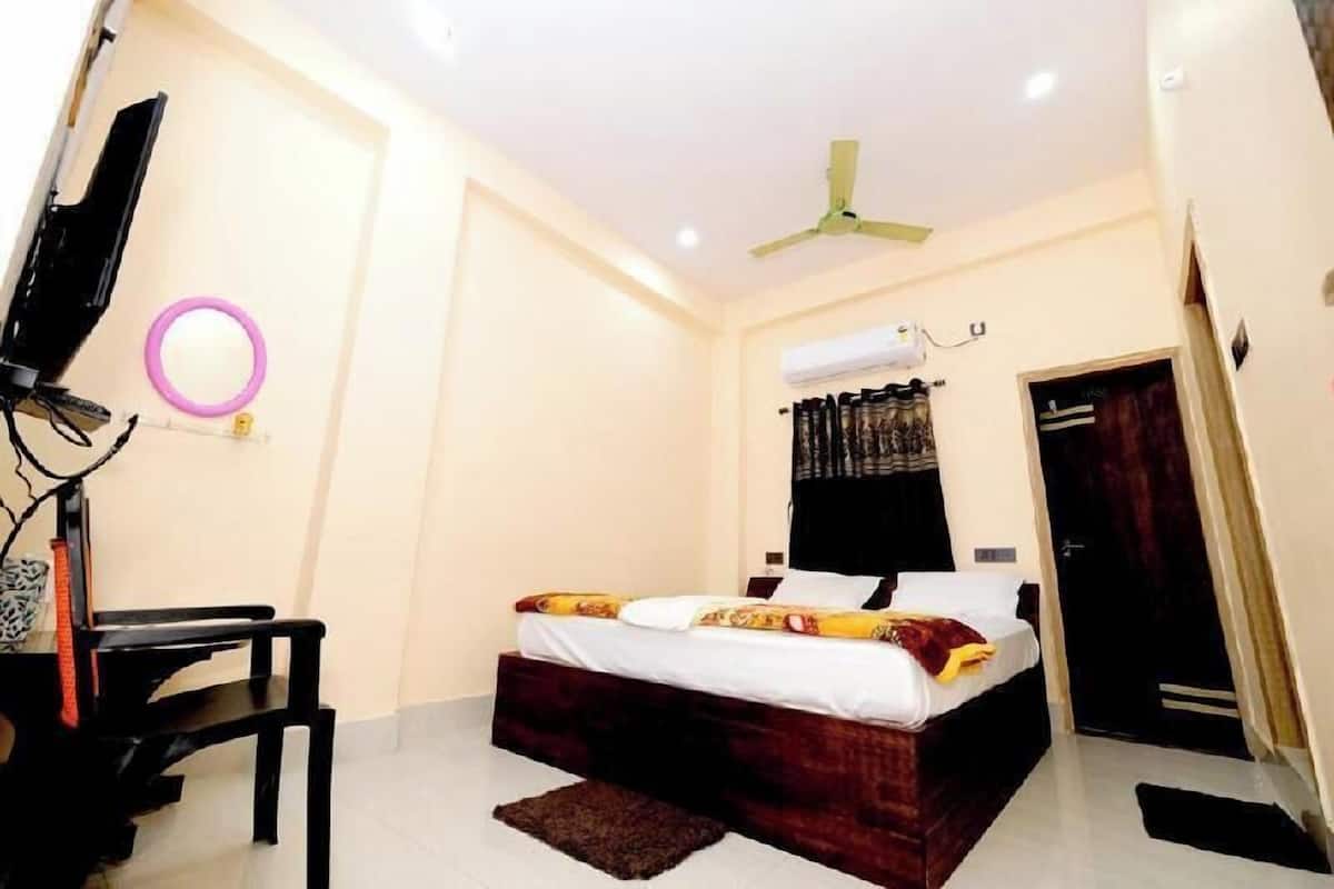 A bedroom with a bed, a desk, a chair, a ceiling fan, and a door.