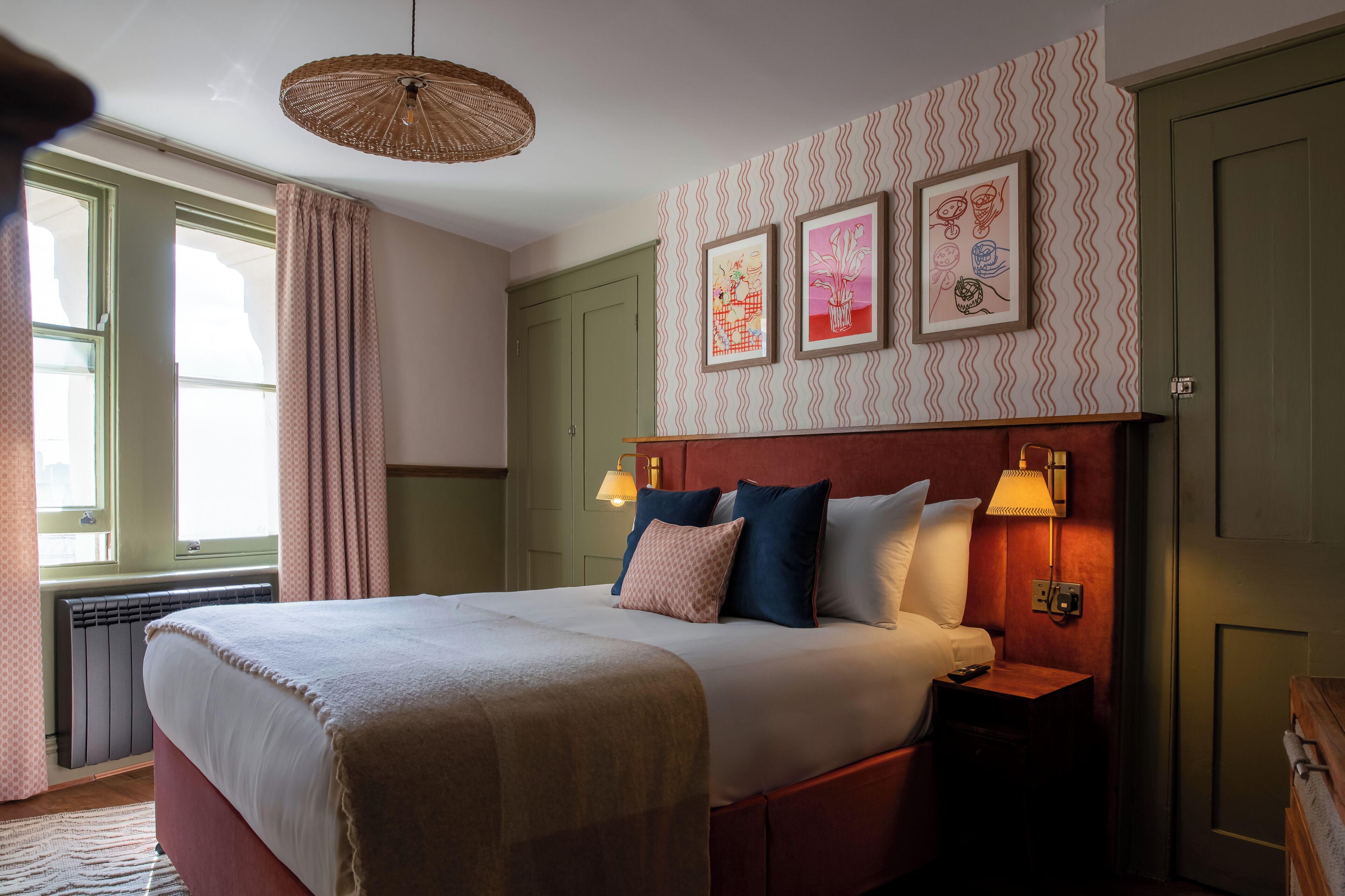 A neatly made bed with a headboard, bedside lamps, and artwork on the wall.