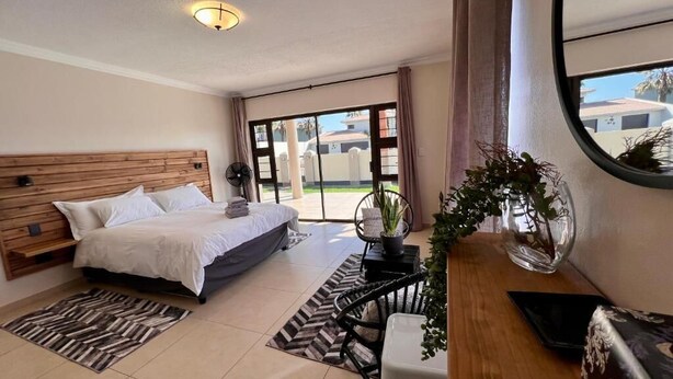 Une chambre d’hôtel avec un lit, un bureau, une chaise, une plante en pot et une vue sur l’extérieur.