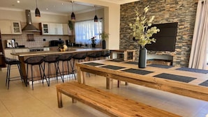 Une cuisine moderne dotée d’un grand îlot central, de tabourets de bar et d’une table à manger avec des bancs.