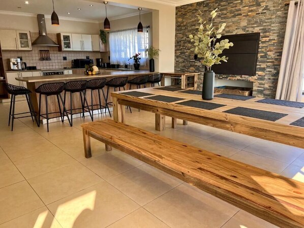 A modern kitchen with a large island, bar stools, and a dining table with benches. - Spacious 6-bedroom house, full equipped, in wonderful Swakopmund with WiFi (Swakopmund)