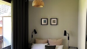 Una cama bien hecha con un edredón gris, dos almohadas, una mesita de noche con una lámpara y una lámpara colgante.