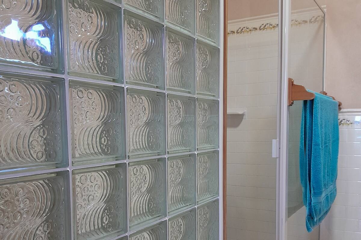A bathroom with a glass shower enclosure, a towel rack, and a tiled floor.