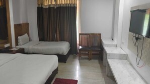 A hotel room with two beds, a desk, a chair, a TV mounted on the wall, and a window with curtains. - The Park Ambanc-New Delhi (New Delhi)