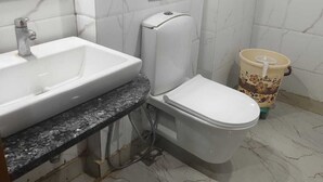 A bathroom with a white sink, toilet, and marble-patterned walls. - The Park Ambanc-New Delhi (New Delhi)