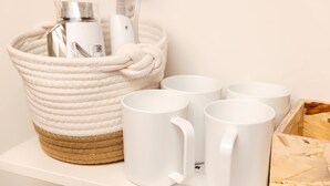 Un panier en osier blanc contenant une bouteille, une brosse à dents et une tasse.