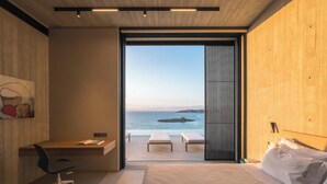 A modern hotel room with a large bed, a desk, and a view of the sea. - Coastal Villa Defined by Detail & Sleek Simplicity by etouri (Chania)