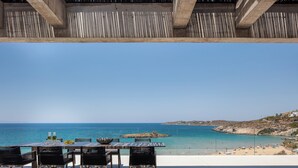 A terrace with a table and chairs facing a beach. - Coastal Villa Defined by Detail & Sleek Simplicity by etouri (Chania)