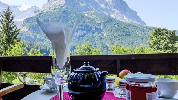 A table with a teapot, cups, and food items, overlooking a mountain. - Chalet Mettli by Interhome (Grindelwald)