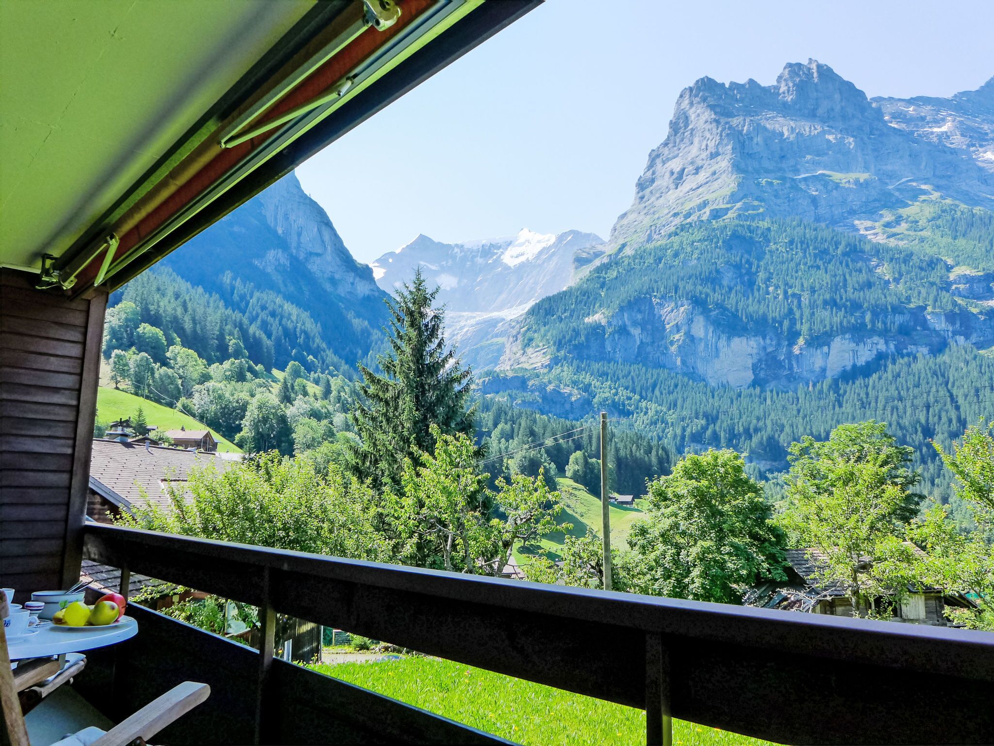 A balcony with a view of a mountainous landscape, including a prominent peak and forested areas.