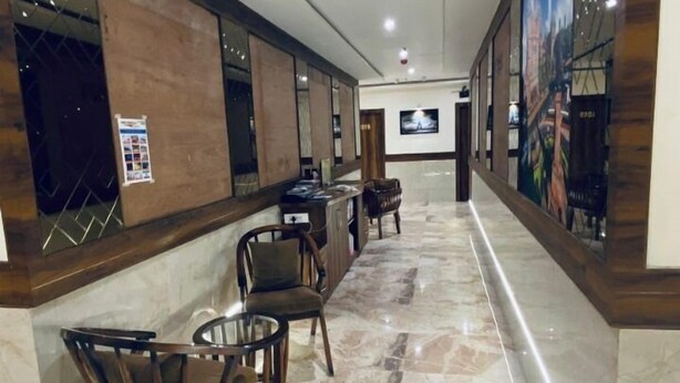 A hotel lobby with a long reception desk, several wooden chairs, and a marble floor. - Hotel BKC Prime  (Mumbai)