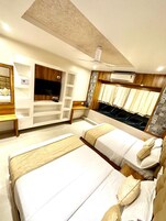 A hotel room with two beds, a TV, a wardrobe, and an air conditioning unit.