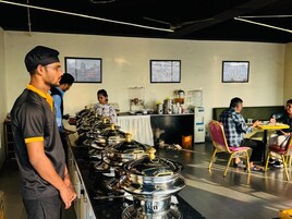 A buffet setup with multiple serving stations, a counter with food items, and a seating area with tables and chairs.
