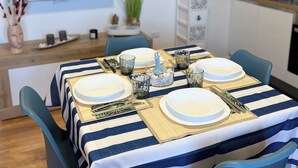 Un comedor con mantel a rayas, sillas azules y un televisor montado en la pared.