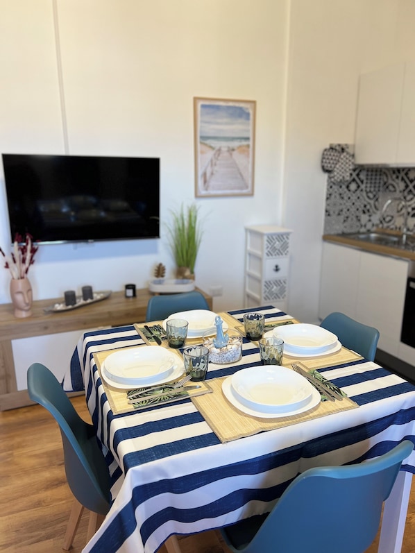 A dining area with a striped tablecloth, blue chairs, and a TV mounted on the wall.