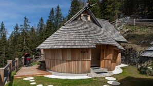 A wooden cabin with a sloped roof, a small window, and a wooden deck leading to the entrance.