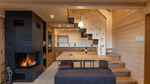 A modern kitchen with a built-in fireplace, wooden paneling, and a dining area with a bench.