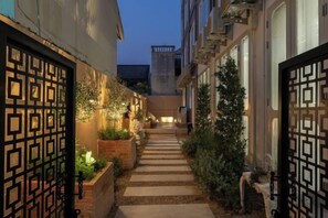 A narrow alleyway with a stone pathway, flanked by buildings with decorative gates and potted plants. - Nimano Suites (Chiang Mai)