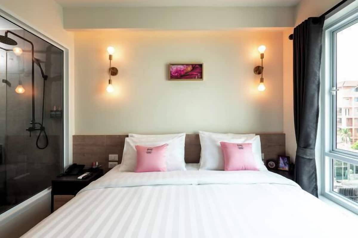 Habitació d'hotel amb un llit gran, dutxa i finestra amb cortines.