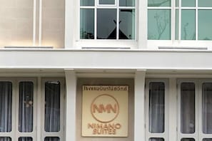 A building with a sign that reads "NIMANO SUITES" and Thai text above it.