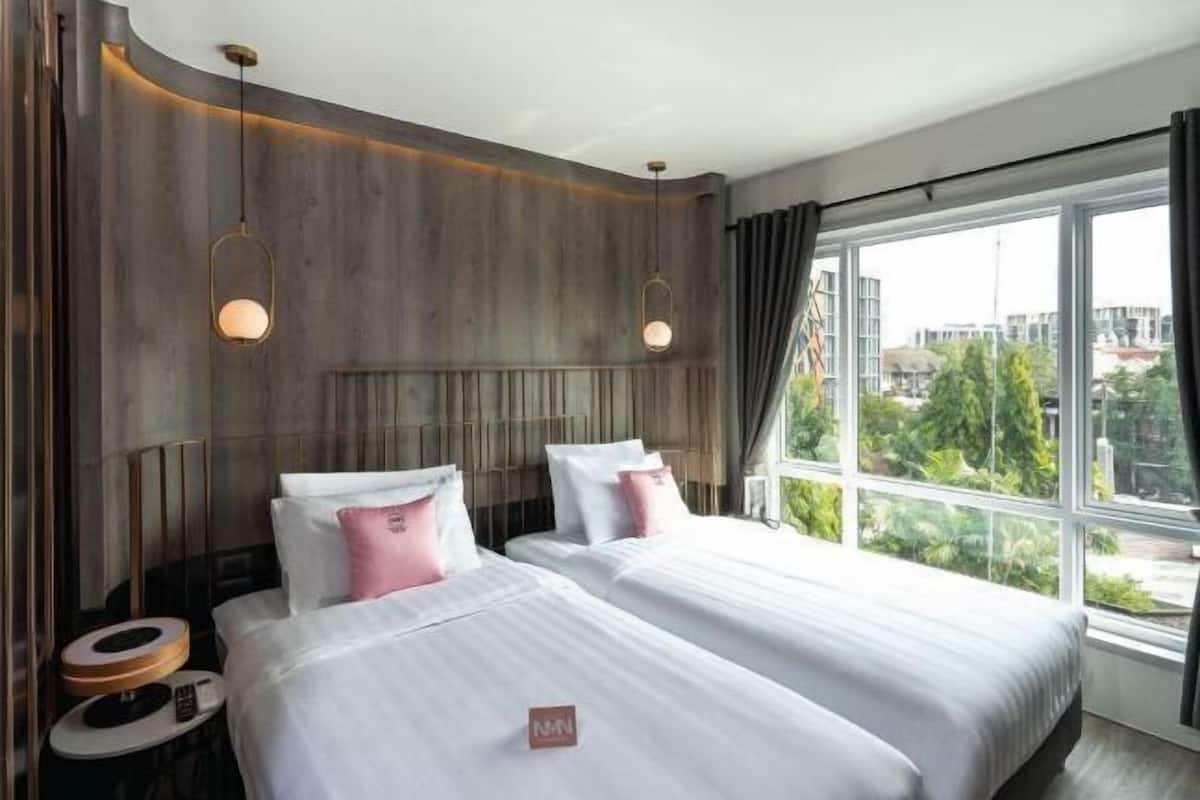 Habitació d'hotel amb dos llits, una finestra gran i vistes a la ciutat.