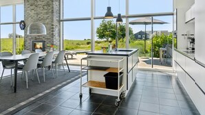Eine moderne Küche mit großen Fenstern, einem Essbereich mit Stühlen und einem Kamin.