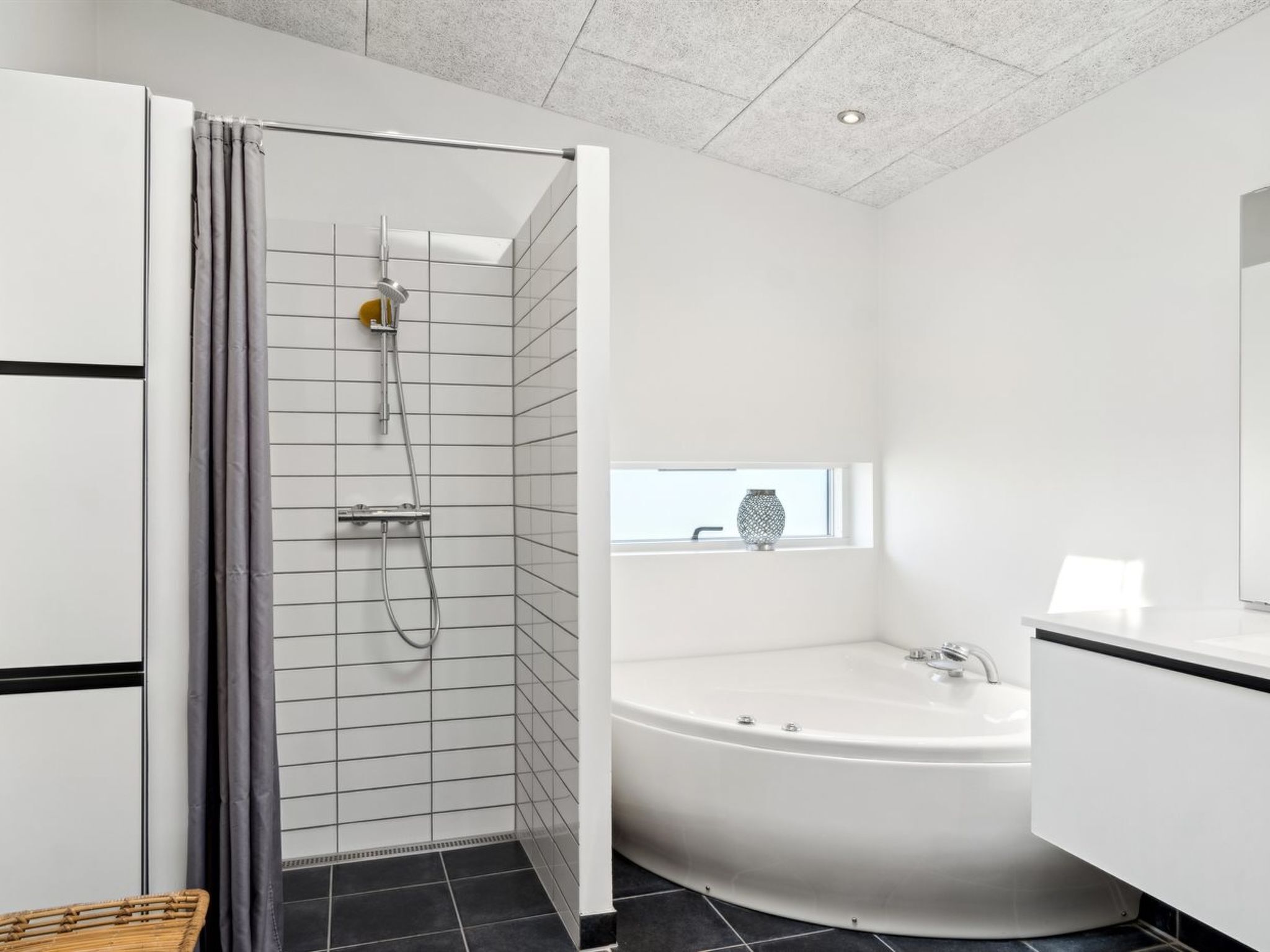 A modern bathroom with a walk-in shower, a freestanding bathtub, and a window with a view.