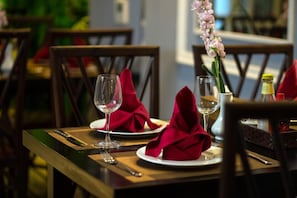 A dining table set with red napkins, wine glasses, and a vase of flowers. - 22land 71 Hang Bong Hotel (Hanoi)