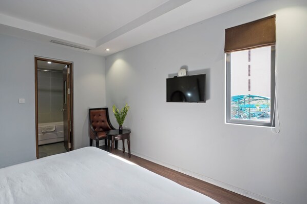 A modern hotel room with a large bed, a small table with a plant, a TV mounted on the wall, and a window with a view of a bridge. - 22land 71 Hang Bong Hotel (Hanoi)