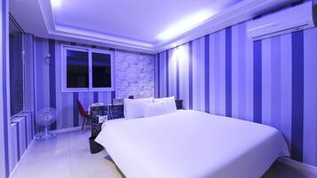 A bedroom with a bed, a window, a fan, and striped walls.