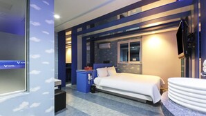 Une chambre d’hôtel comprenant un lit, un bureau, une chaise, une télévision et une salle de bain avec un lavabo et un miroir.