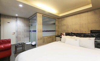 Habitación de hotel con una cama grande, una silla roja, una mesita y un espejo en la pared.