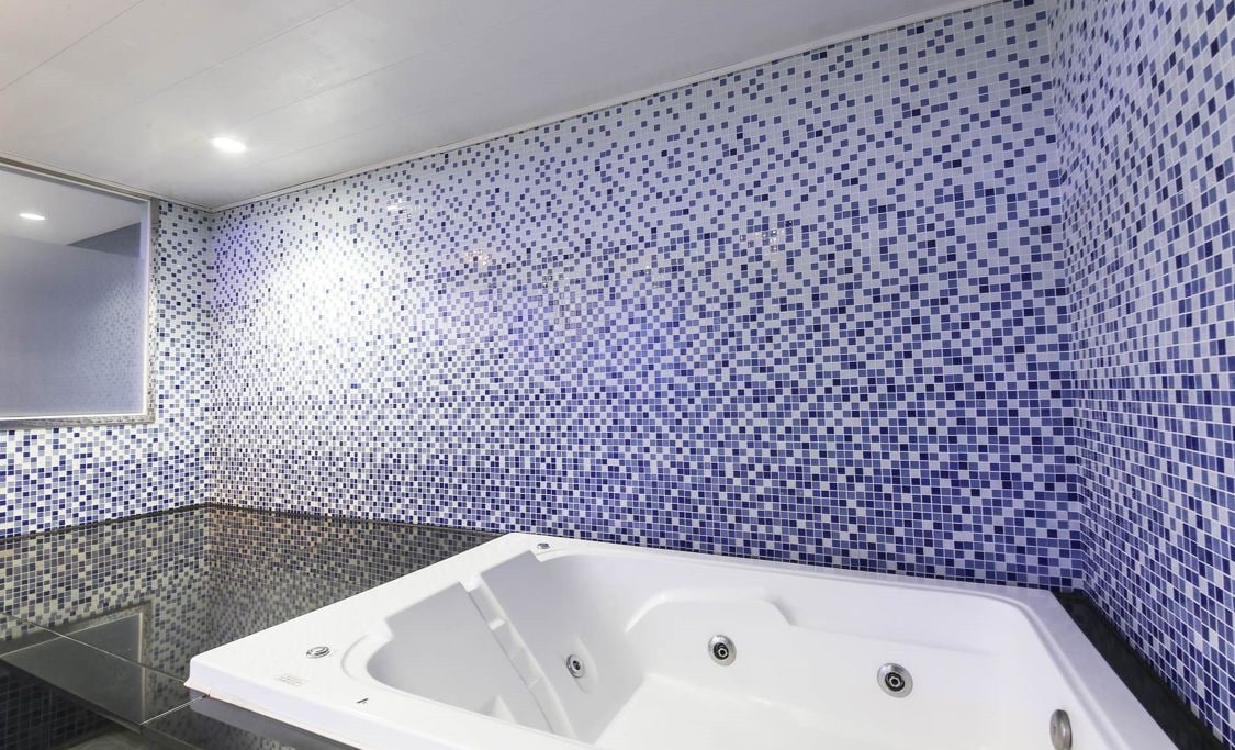 A modern bathroom with a large bathtub, tiled walls, and a glass shower enclosure.
