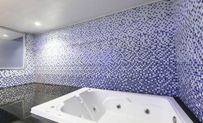 A modern bathroom with a large bathtub, tiled walls, and a glass shower enclosure. - Songjeong V Hotel (Busan)