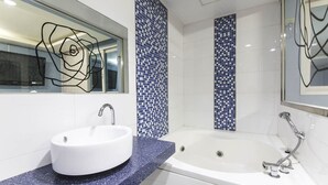Une salle de bain moderne avec un lavabo blanc, une baignoire et des murs recouverts de carreaux de mosaïque bleus.